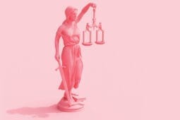 Lady justice holding scales and sword on pink background