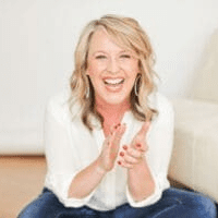 Seated woman in jeans clapping hands and smiling.