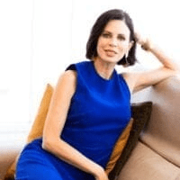 A woman with short brown hair in a blue dress on a couch.